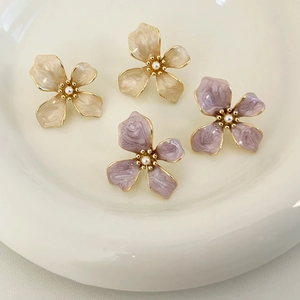 Detail of flower stud earrings with enamel petals and pearl center on white tray