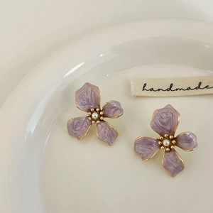 Detail of purple enamel flower earrings with gold edges and a center pearl inlay
