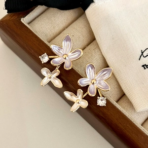 Detail of floral enamel stud earrings with purple flowers and zircons in a jewelry box