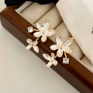 Detail of floral enamel stud earrings with zircon stones on beige velvet jewelry box