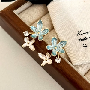 Detail of floral earrings featuring blue enamel petals and sparkling zircon accents