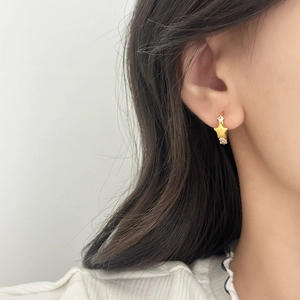 Exquisite gold star-shaped stud earrings with inlaid zircon on woman's ear