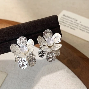 Macro detail of silver flower earrings with zircon centers on dark velvet stand