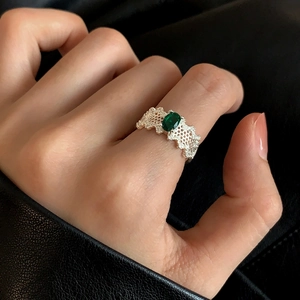 Macro shot of vintage silver lace ring featuring an oval dark green gemstone on finger