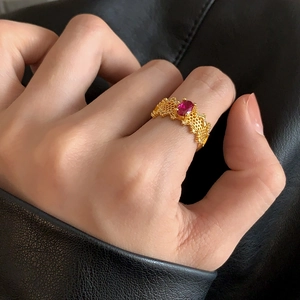 Detailed shot of a gold lace ring with red oval gemstone and white zircon pavé on model
