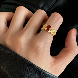 Detailed shot of a vintage gold lace ring with an oval red gemstone on a hand