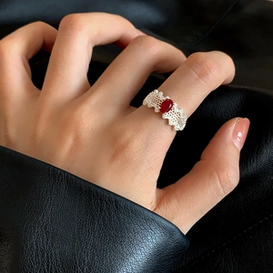 Macro detail of silver open ring with red oval gemstone and honeycomb hollow texture