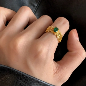 Detailed view of vintage gold ring with oval green gemstone and honeycomb hollow pattern