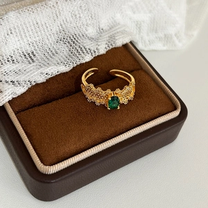 Macro detail of gold adjustable ring featuring a green oval stone and coral texture
