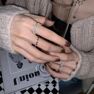 Close-up of sparkling zircon open ring set worn by model holding a glass