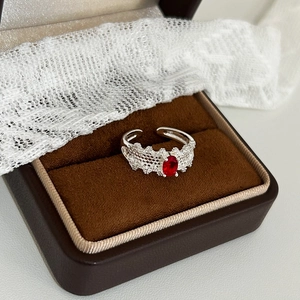 Detailed view of adjustable lace ring with a large oval red zircon in a jewelry box