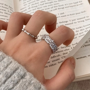 Close-up of stacked silver zircon rings worn against an elegant book background