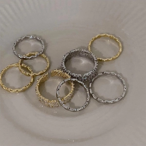 Macro shot of assorted stackable rings with wave textures and zircon inlays on white ceramic