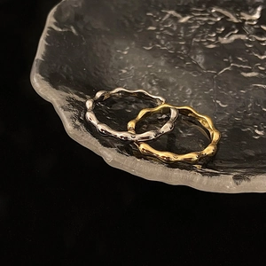 Macro detail of high-polish gold and silver wavy stackable rings on textured glass