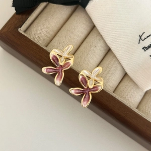 Macro detail of floral stud earrings with gradient pink enamel and golden metallic edges