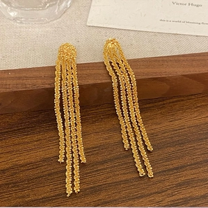 Eleganti orecchini lunghi a nappa dorata con texture a catena serpente su legno