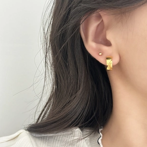 Minimalist gold hoop earrings with irregular wrinkled texture and small ball stud