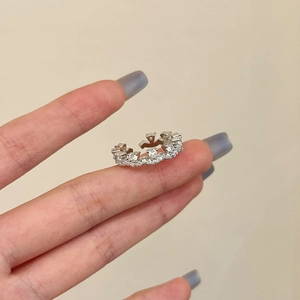 Macro detail of silver crown ring with cubic zirconia on female hand in warm setting