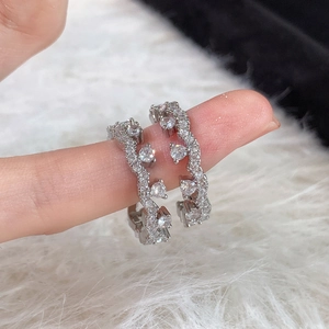 Detailed view of silver wave rings with cubic zirconia stones worn on models hand