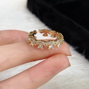 Macro view of gold wavy ring with white zircon stones on a white fur and black velvet background