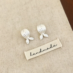 Vue détaillée de boucles d'oreilles queue de poisson argentées sur fond de toile