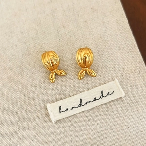 Détail des boucles d'oreilles queue de poisson dorées vintage sur fond en lin fait main