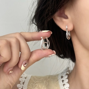 Minimalist silver irregular double loop earrings shown in hand and worn by a model