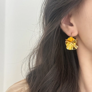 Elegant gold metal petal-shaped earrings with irregular folded design on model