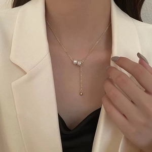 Collier en perles dorées avec barillet serti de zircons et pampille porté par un mannequin