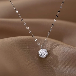 Close-up of sparkling zircon pendant with six-prong setting on silver chain over silk