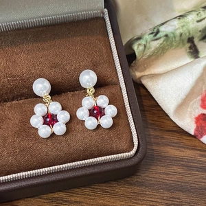 Detail view of pearl flower earrings with red center in a luxury velvet jewelry box