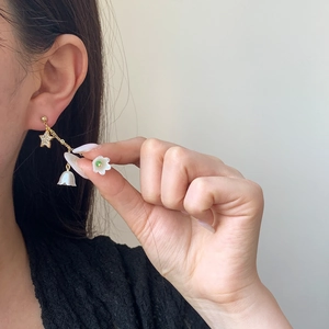 Boucles d'oreilles étoile et muguet avec chaîne dorée et cristaux portées par un mannequin