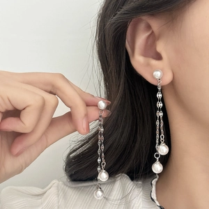Elegant long pearl tassel earrings with silver metal chains shown on a model
