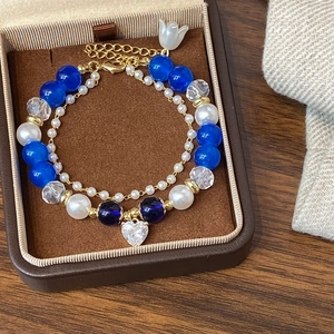 Close-up of double-layered beaded bracelet with blue crystals and a heart-shaped pendant