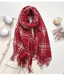 Detail of red and white two-tone scarf with fine fringe tassels on a knit sweater