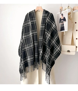 Detail of classic black and white plaid scarf with fine fringe on beige coat
