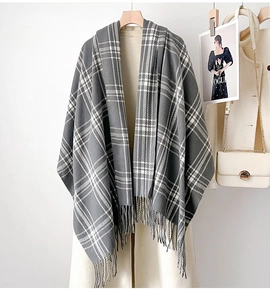Close-up of a grey and white checkered tassel shawl styled on an autumn wool coat