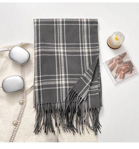 Detailed texture of thick grey and white plaid winter scarf with tassel fringe edges