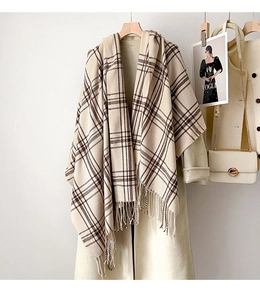 Close-up of beige and brown checkered scarf with fringe hanging on an overcoat