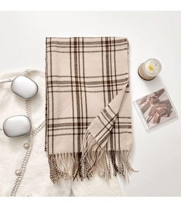 Flat lay of a beige and brown checkered scarf with fringe next to an aesthetic candle