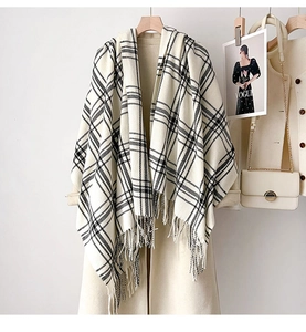 Detail of soft black and white checkered scarf with fringe tassels on beige coat