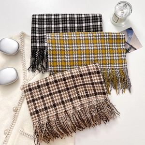 Three premium checkered scarves with tassels in autumn colors on a minimalist white backdrop