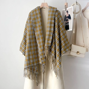 Classic plaid scarf with fringes styled on a beige wool coat for autumn and winter