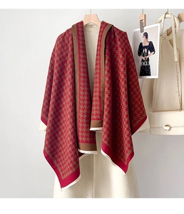 Dettaglio di sciarpa pied de poule rossa e marrone con frange su cappotto bianco