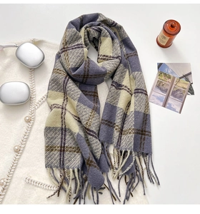 Detailed view of heavy winter plaid scarf with fringe on a white knit sweater