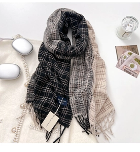 Flat lay di sciarpa a quadri con nappe nera, beige e marrone con cuffie e candela