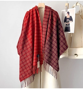 Dettaglio di sciarpa a quadri rossi con lunghe frange drappeggiata su cappotto bianco