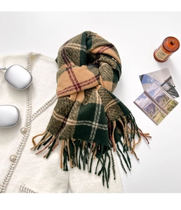 Close-up of thick plaid knit scarf with tassels over a white tweed coat background