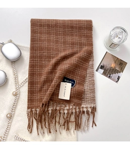 Primo piano dell'sciarpa a maglia a quadri marroni e beige con nappe bicolore e etichette