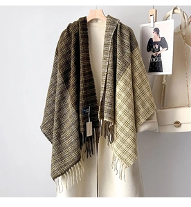 Dettaglio della trama di una spessa sciarpa a quadri con frange su un cappotto beige